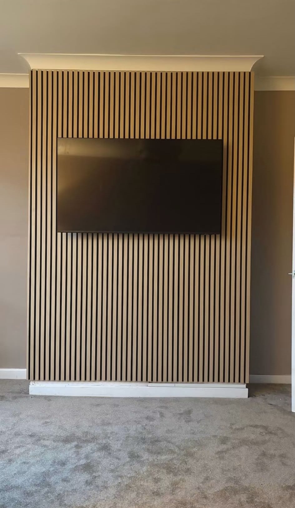 TV mounted flush into a custom slatted timber feature wall — ProFix Home Services Glasgow